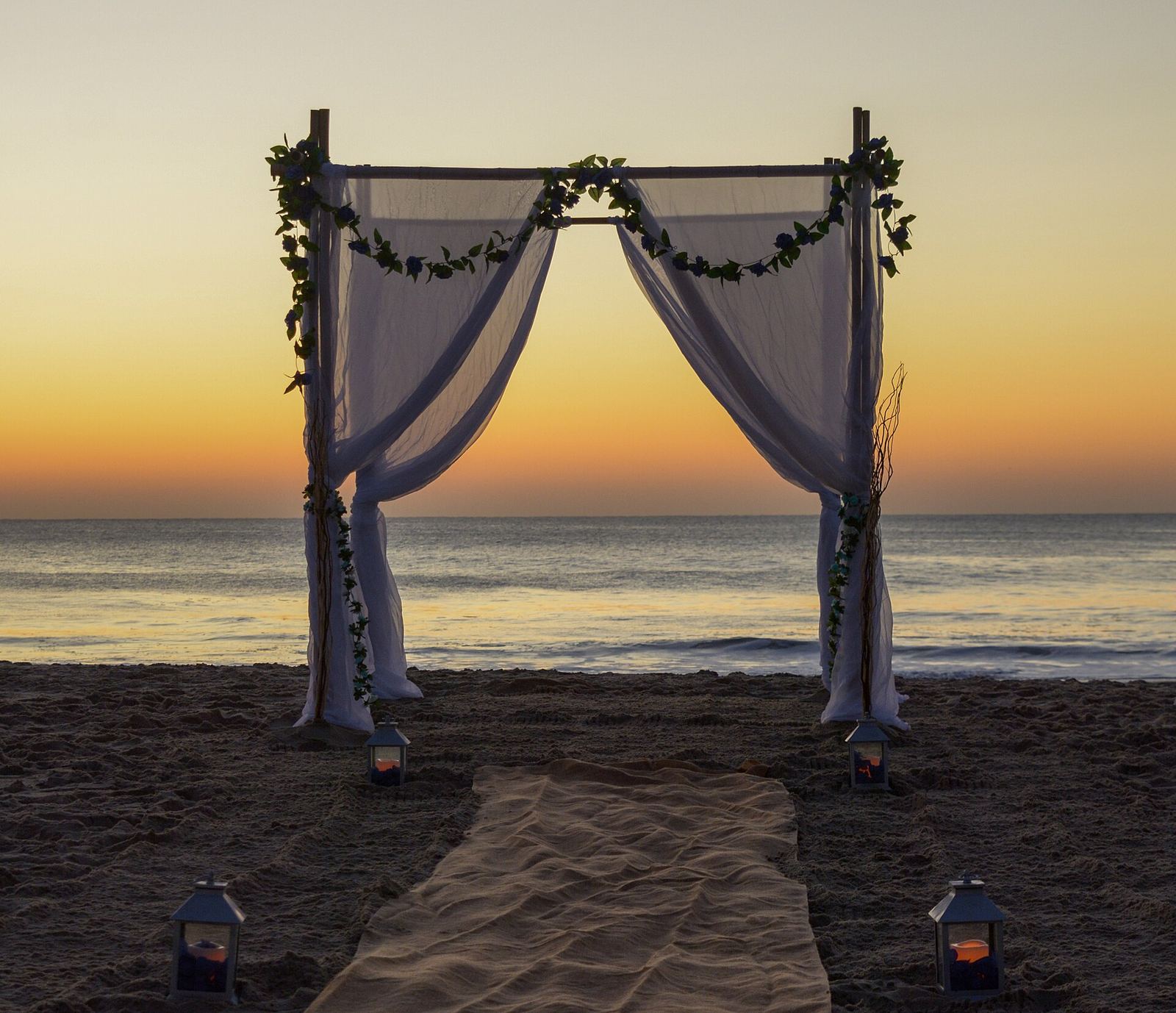 A draped wedding arch on the beach at sunset