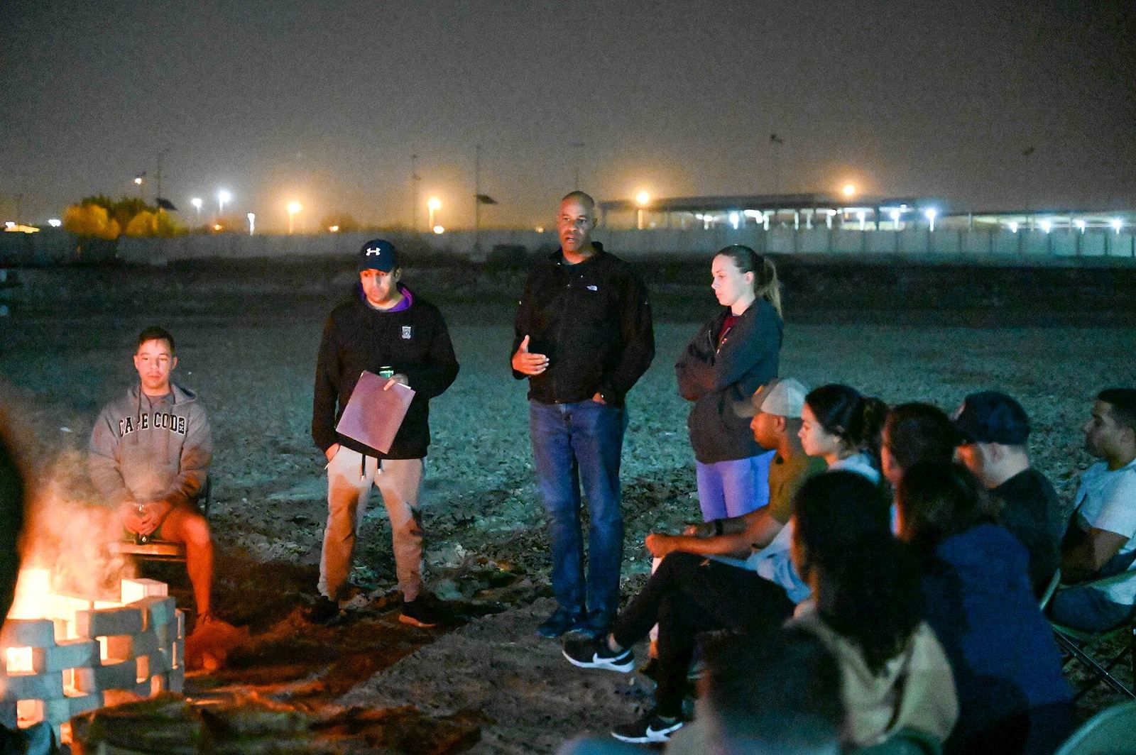 Guests gathered around a beach bonfire at night